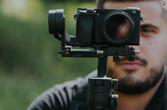A videographer taking content through a black camera positioned in a tripod