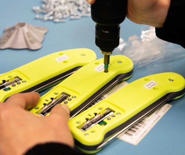 Hands screwing together the Thermapen backs at a work station with Thermapen internals visible a little bit